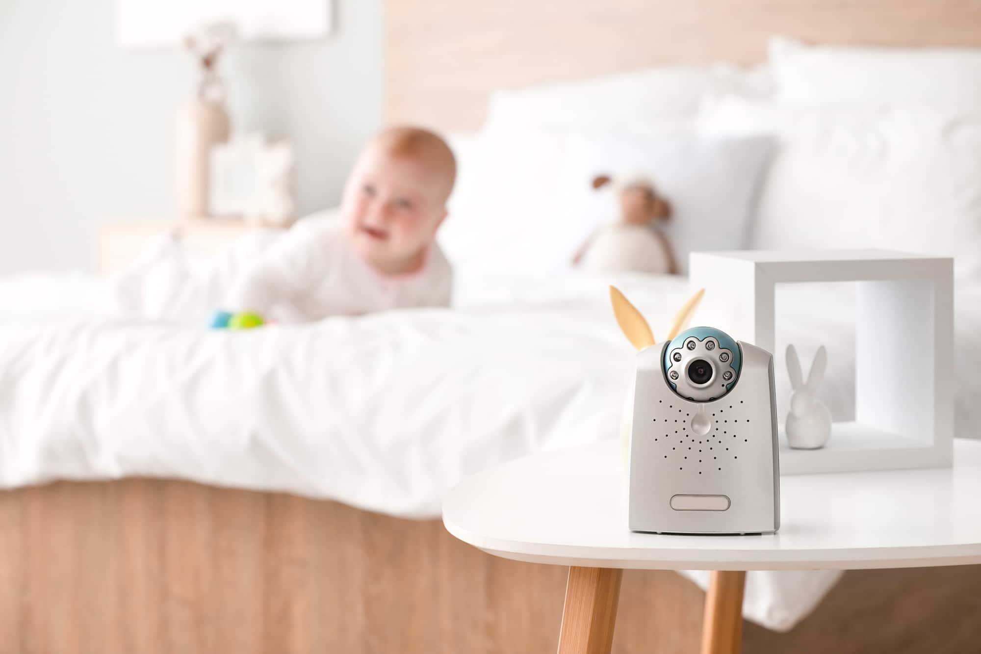 Baby monitor on a bedside table with baby in background